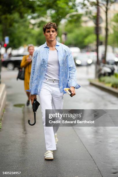 Guest wears a white tank-top, a blue with embroidered white pattern open shirt, white denim jeans pants, white socks, pale yellow shiny leather...