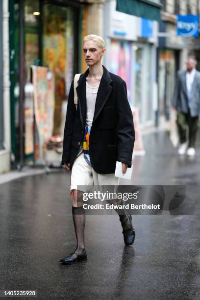 Guest wears a beige tank-top, a black felt oversized blazer jacket, a beige leather shoulder bag, a blue / yellow / orange print pattern silk scarf...