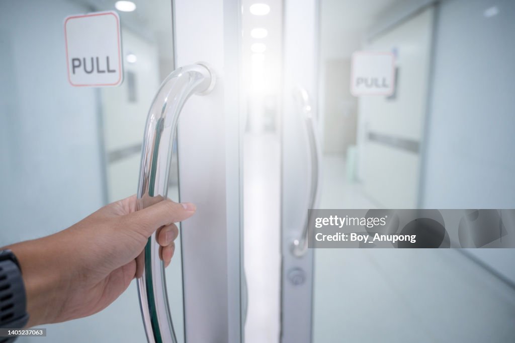 Someone hand pulling door for entering to O.R (Operating Room) area in hospital.