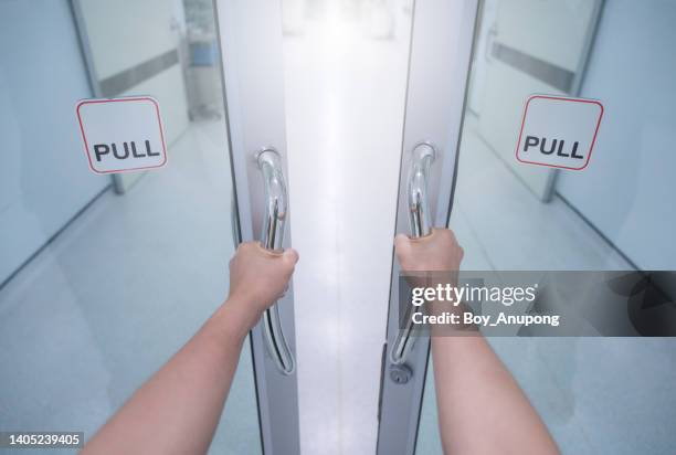 someone hands pulling door for entering to o.r (operating room) area in hospital. - er door stock pictures, royalty-free photos & images