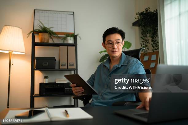 freelance having virtual work video conference on laptop computer while holding digital tablet at home office. - mentoring virtual stock pictures, royalty-free photos & images