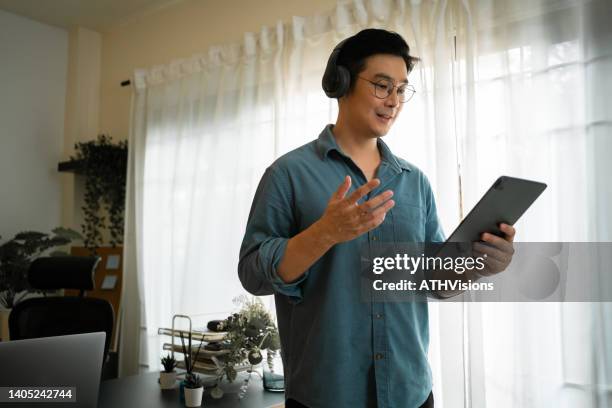 smiling entrepreneur man talking with shipping on digital tablet at home - mature man using phone tablet stock pictures, royalty-free photos & images