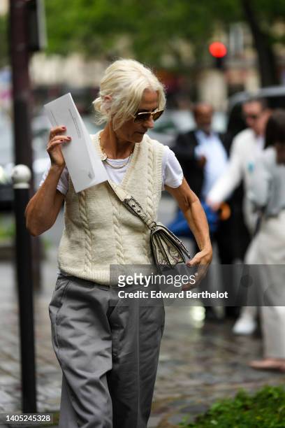 Guest wears sunglasses, a white t-shirt, a pale yellow braided wool sleeveless pullover, a beige and black print pattern leather crossbody bag, gray...