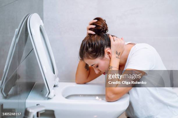 young woman feeling sick, throwing up sitting near toilet. gestational toxicosis - vomit stock pictures, royalty-free photos & images