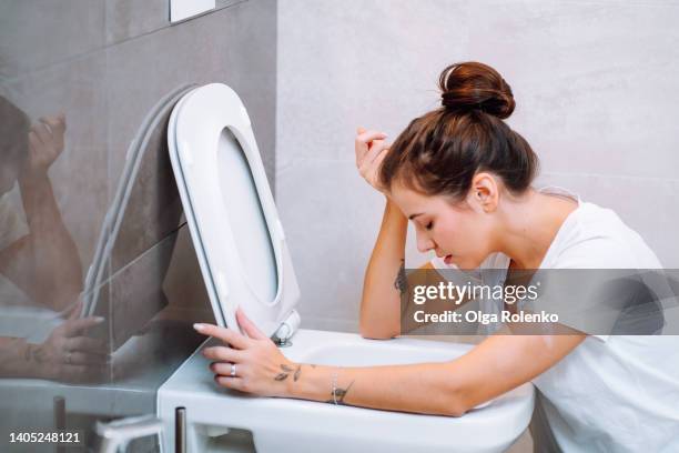 young woman feeling sick, throwing up, vomiting in toilet - morning sickness fotografías e imágenes de stock