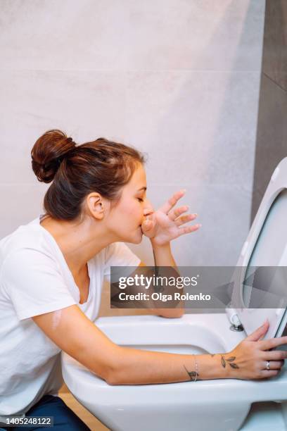 young woman feeling sick, throwing up sitting near toilet. food poisoning - gastroentérite photos et images de collection