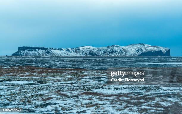 hjorleifshofdi is a 221-metre tall mountain located on a black sand plain, near the southernmost tip of iceland, coverd in snow - snow coverd stock pictures, royalty-free photos & images