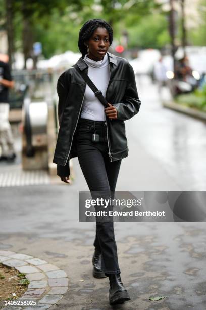 Guest wears a black scarf, silver earrings, a white turtleneck long sleeves t-shirt, a black shiny leather zipper jacket, black denim skinny jeans...