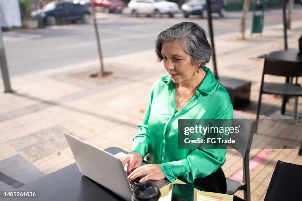 mature businesswoman using laptop in a restaurant - cafe santiago stock pictures, royalty-free photos & images