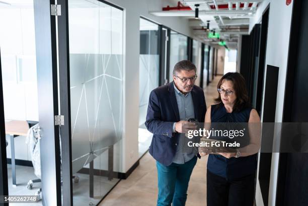 empresarios caminando y hablando en el pasillo de la oficina - director financiero fotografías e imágenes de stock
