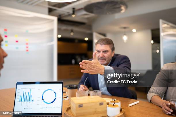 senior businessman gesticulating during business meeting in the office - cfo stock pictures, royalty-free photos & images