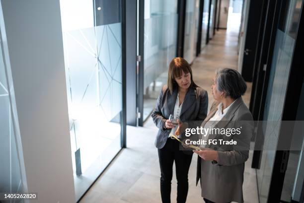 businesspeople walking and talking in the office's corridor - chief financial officers stock pictures, royalty-free photos & images