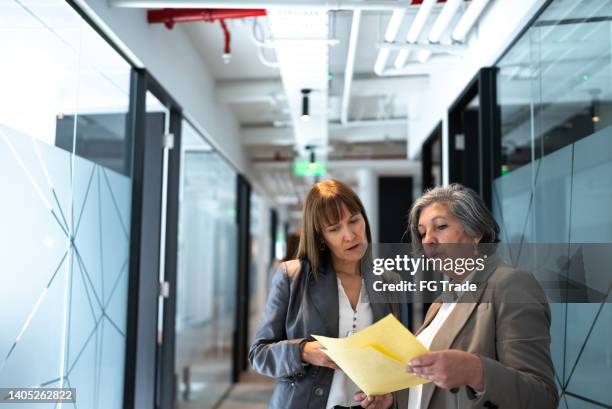 des gens d’affaires marchant et parlant dans le couloir du bureau - chili woman photos et images de collection