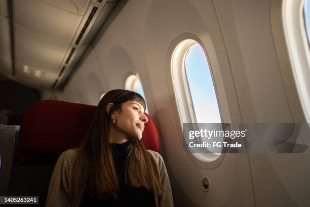 junge frau, die mit dem flugzeug reist und aus dem fenster schaut - cabin stock-fotos und bilder