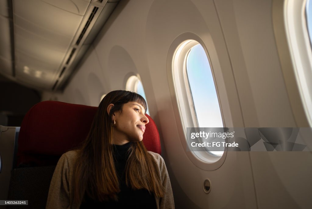 Young woman traveling by plane looking out the window