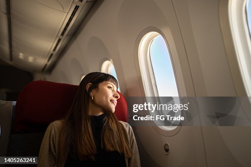 Young woman traveling by plane looking out the window Young woman traveling by plane looking out the window