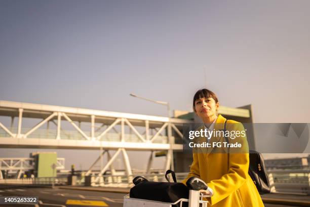 young woman pushing luggage at the airport - reopening ceremony stock pictures, royalty-free photos & images