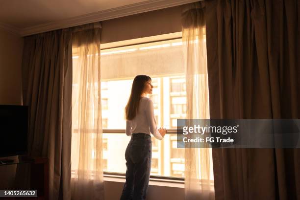 young woman contemplating in room window - frayed stock pictures, royalty-free photos & images