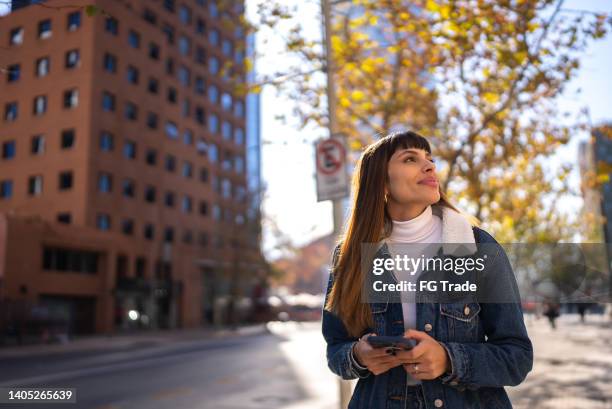 young woman using mobile phone in the city - women phone city facebook tourist stock pictures, royalty-free photos & images