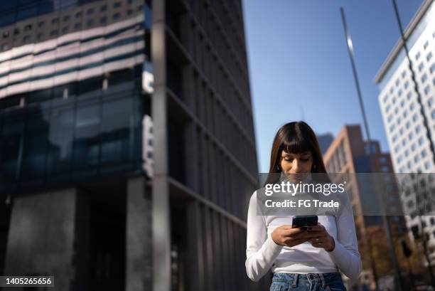 young woman using mobile phone outdoors - fringing stock pictures, royalty-free photos & images