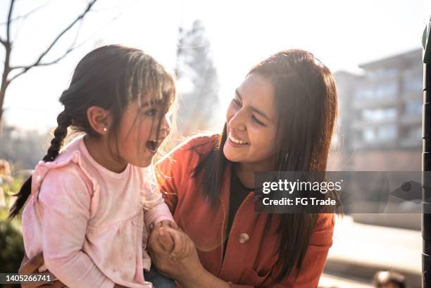 mother helping daughter playing in the playground - chilean people stock pictures, royalty-free photos & images