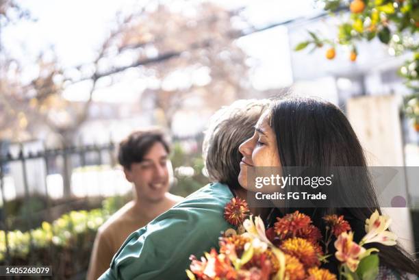 mother receiving a bouquet from daughter at home - flowers copy space stock pictures, royalty-free photos & images