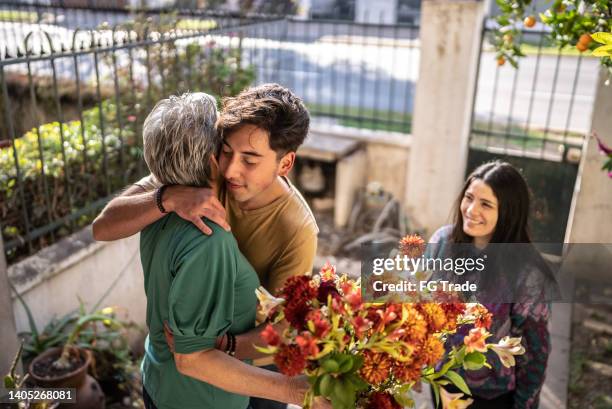 mère recevant un bouquet de sa fille et de son fils à la maison - mothers day flowers photos et images de collection