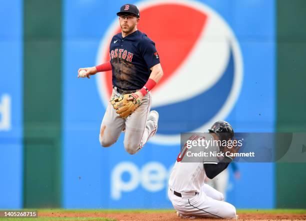 Trevor Story of the Boston Red Sox leaps over Andrés Giménez of the Cleveland Guardians after forcing Giménez out at second base during the second...