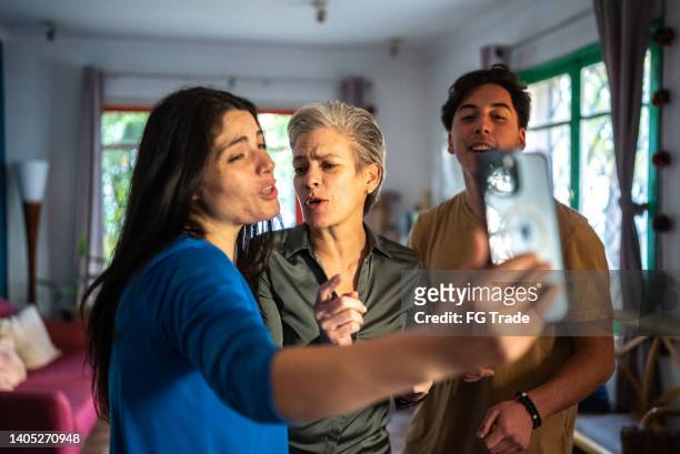 family dancing while daughter film or photograph on the mobile phone at home - no 2012 chilean film stockfoto's en -beelden