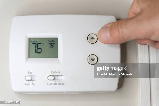 adjusting the thermostat on the air conditioner to save money - termostato foto e immagini stock