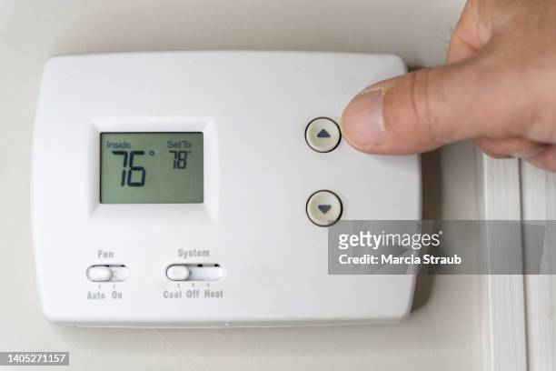 adjusting  the thermostat on the air conditioner to save money - heating home stock pictures, royalty-free photos & images