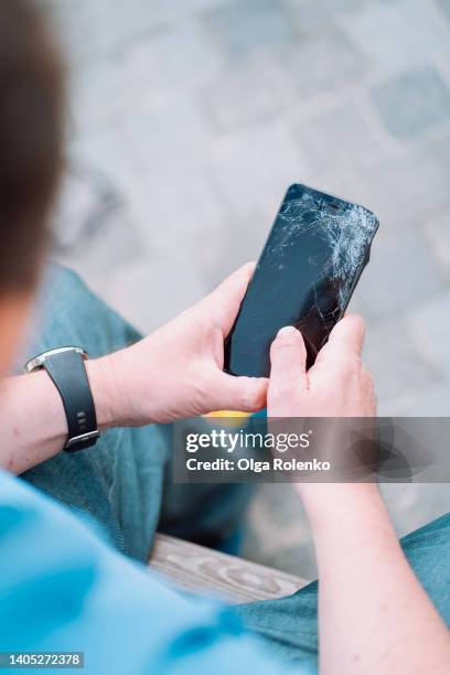 unrecognizable man hands holding black damaged, cracked smartphone, checking how it is working - broken finger ストックフォトと画像