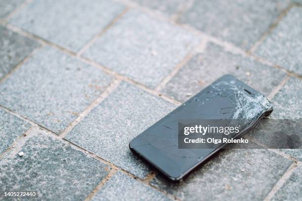 broken smartphone with lying on the ground in the street. scratched screen - cracked iphone stock pictures, royalty-free photos & images