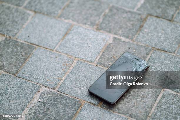 broken smartphone with lying on the ground in the street - repairing iphone stock pictures, royalty-free photos & images