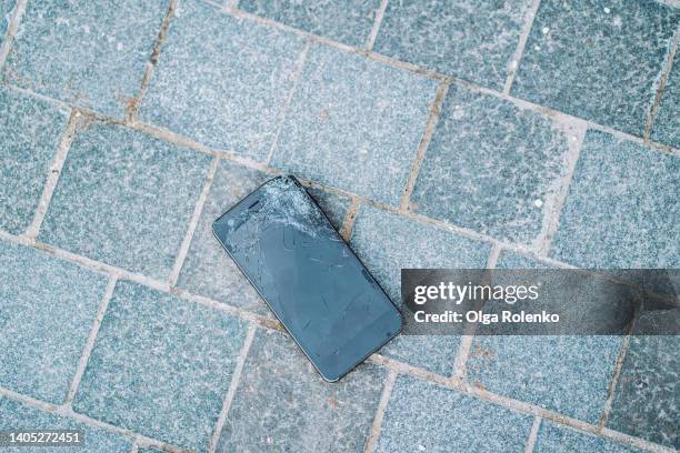 broken smartphone lying on the ground in the street. scratched display. top view - gebrochen stock-fotos und bilder