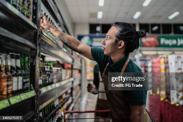 non-binary person working in a supermarket - conagra general mills brand products on the shelf ahead of earns stockfoto's en -beelden