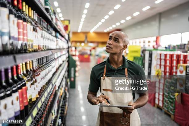 young man working with a digital tablet in a supermarket - tablet alcohol stock pictures, royalty-free photos & images