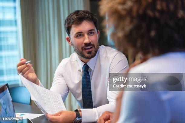 business man talking to a business woman while holding a document. he is happy and smiling. he is wearing a tie. - job interview male stock pictures, royalty-free photos & images