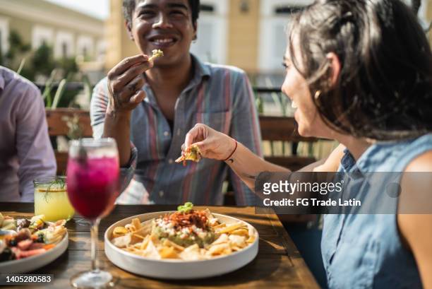 friends eating guacamole at a restaurant - mexican food stockfoto's en -beelden
