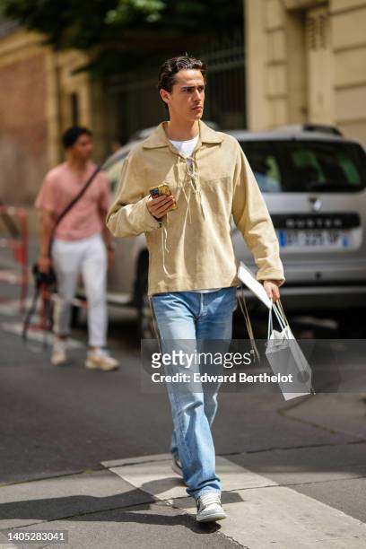 Guest wears a white t-shirt, a pale yellow suede jacket, blue faded denim large pants, white / gray / black shiny leather Air Force One sneakers from...