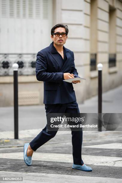 Guest wears black sunglasses, a black blazer jacket, black matching suit pants, pale blue loafers , outside the Dior Homme show, during Paris Fashion...