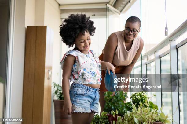 sisters watering plants in balcony - plant breeding stock pictures, royalty-free photos & images