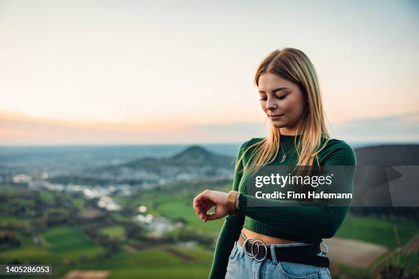 junge blonde frau im freien prüft moderne smartwatch - verspätet stock-fotos und bilder