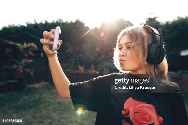 happy teen girl in headphones takes a selfie on the phone or talks on the phone. - child using a smartphone stock pictures, royalty-free photos & images