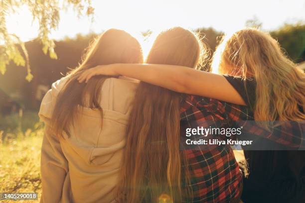 a group of teenage girls hugging from behind on a sunny day. - cute girlfriends stockfoto's en -beelden