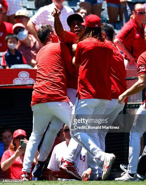 Raisel Iglesias of the Los Angeles Angels is held back during a bench clearing after Jesse Winker of the Seattle Mariners charged the Angels dugout...