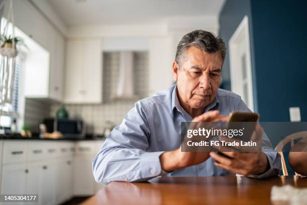 mature man using mobile phone at home - telefoon gebruiken stockfoto's en -beelden