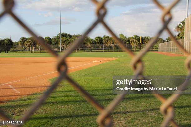 looking through fence at empty baseball field - chain link fence stock-fotos und bilder