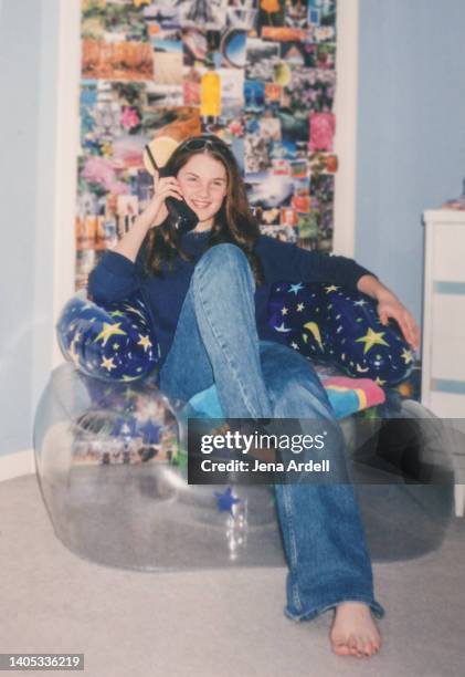 vintage 1990s 2000s teen talking on phone, vintage teen sitting on inflatable chair - 1990 fotografías e imágenes de stock