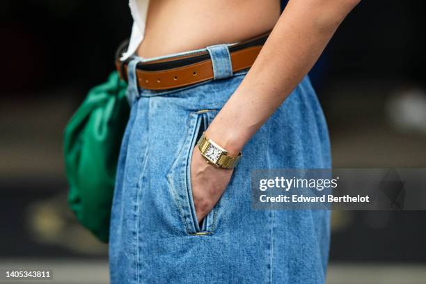 Dree Hemingway wears a white asymmetric cropped t-shirt, a green shiny leather puffy handbag from Bottega Veneta, gold rings, a gold watch, a camel...